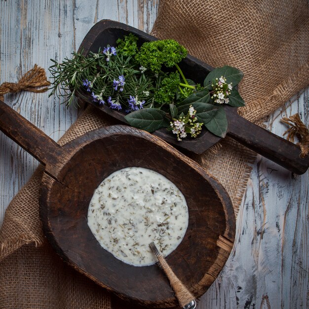 Top view dovga with rosemary leaves and spoon in wooden plate