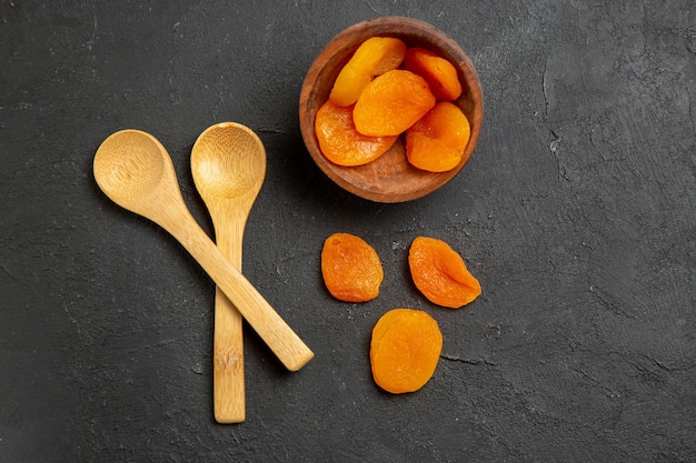 Top view dried apricot raisins with wooden spoons on dark surface dry fruit raisin