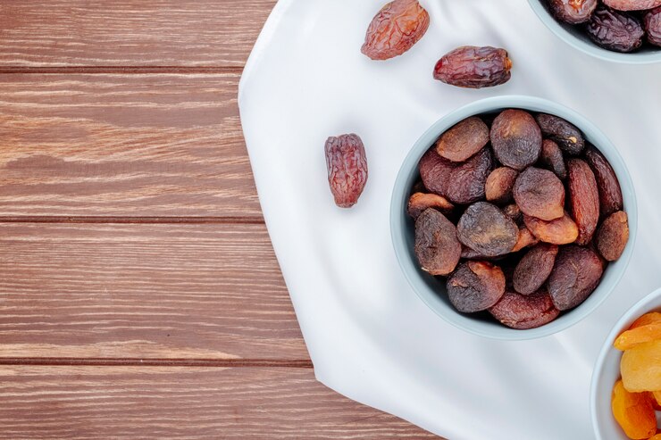 Free Photo top view of dried apricots in a bowl and with dried dates on wooden background with copy space