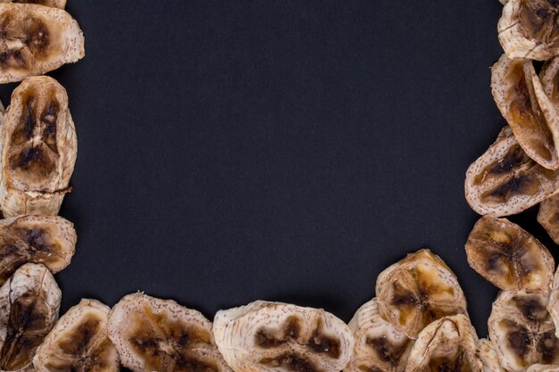 Top view of dried banana chips isolated on black background with copy space