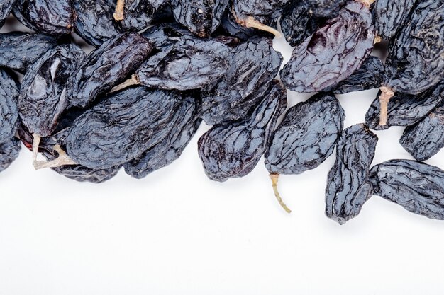 Top view of dried black raisins on white background