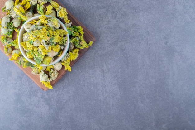 Top view of dried chamomile flowers on wooden board.