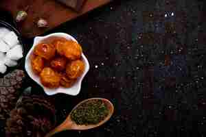 Free photo top view of dried cherry plums in a saucer and a wood spoon with dried peppermint on black with copy space