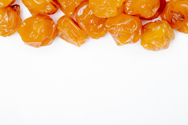 Top view of dried cherry plums on white background with copy space