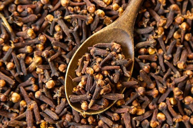 Top view dried cloves with a wooden spoon