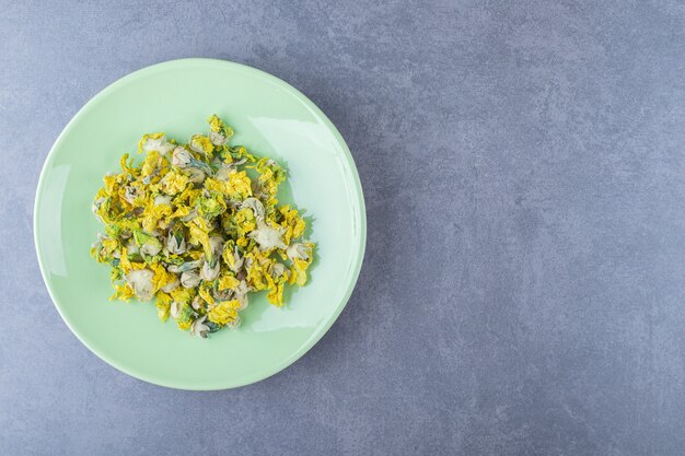 Top view of dried flowers on green plate.