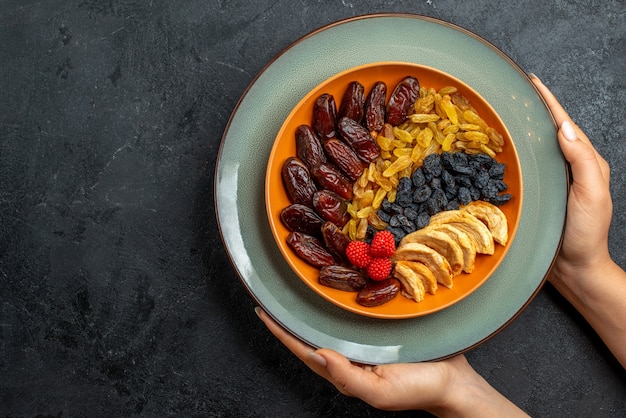 Top view dried fruits with different raisins and snacks on grey space