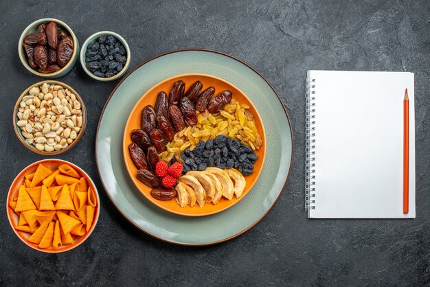 Top view dried fruits with different raisins and snacks on grey space