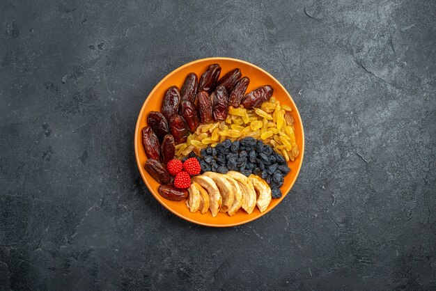 Top view dried fruits with raisins inside plate on grey space