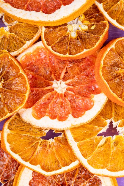 Top view of dried orange and grapefruit slices arranged on purple background