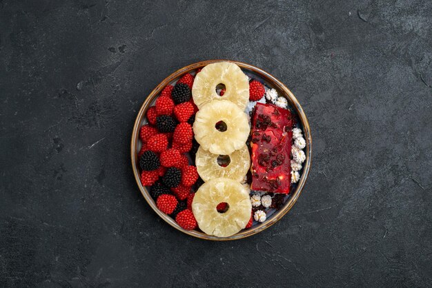 Top view dried pineapple rings with confiture berries on grey surface
