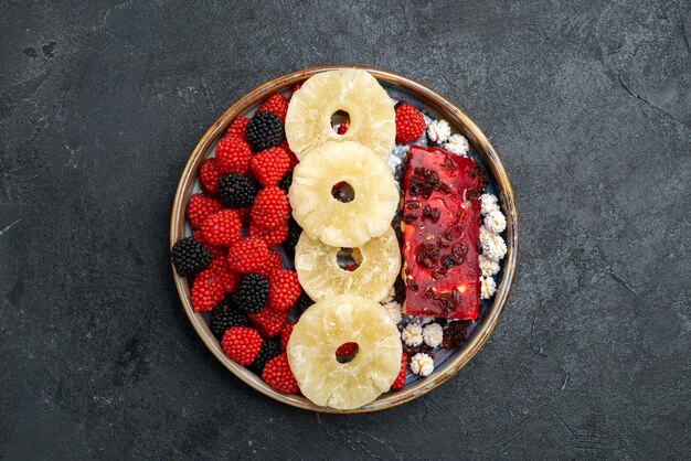 Top view dried pineapple rings with confiture berries on grey surface