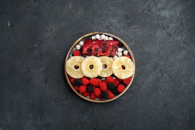 Top view dried pineapple rings with confiture berries on the grey surface