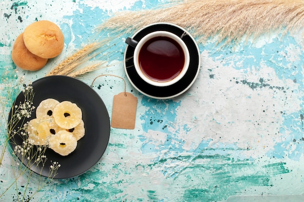 Top view dried pineapple rings with cup of tea on the blue desk cake bake fruit biscuit sweet sugar cookies