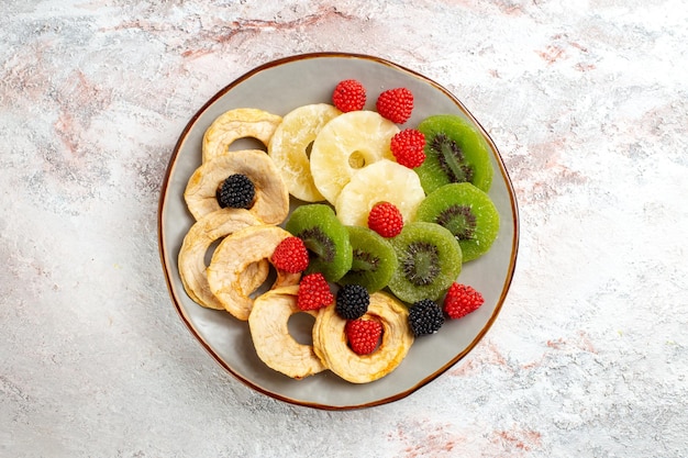 Top view dried pineapple rings with dried kiwis and apples on white surface