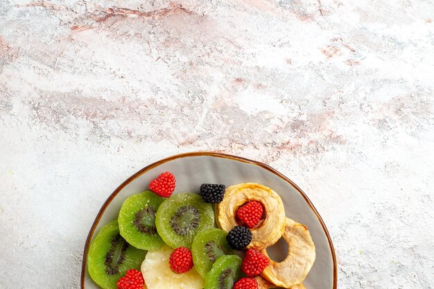 Top view dried pineapple rings with dried kiwis confitures and apples on white surface