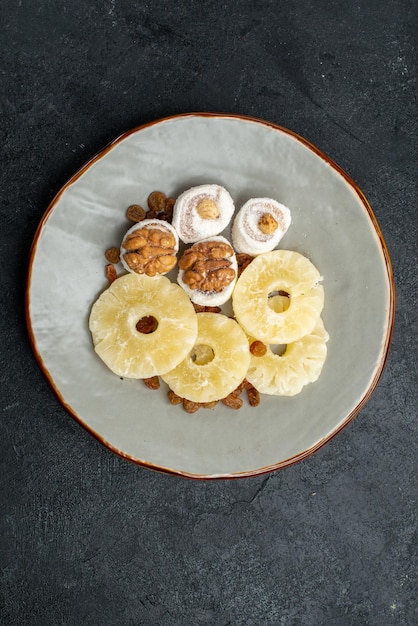 Top view dried pineapple rings with raisins on grey surface