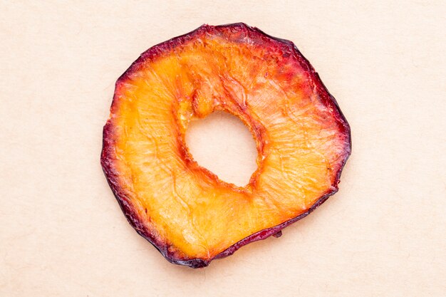 Top view of dried plum slice isolated on brown paper texture background