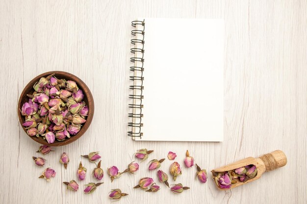 Top view dried purple flowers with notepad on white desk color flower purple copybook