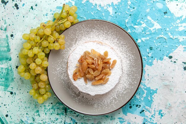 Top view dried raisins from grape with fresh green grapes on light-blue surface