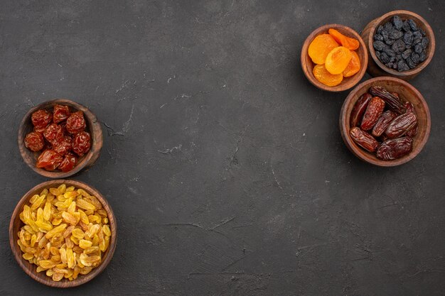 Top view of dried raisins inside little pots on grey surface