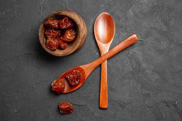 Top view dried raisins with wooden spoons on dark surface dry fruit raisin