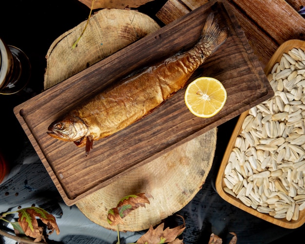 Top view of dried smoked fish served with lemon half