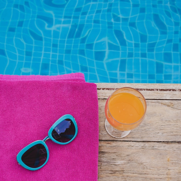 Top view of drink, sunglasses and swimming pool