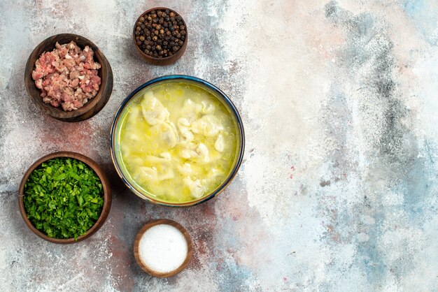 Top view dushbara dumplings soup bowls with meat greens pepper salt on nude surface copy space