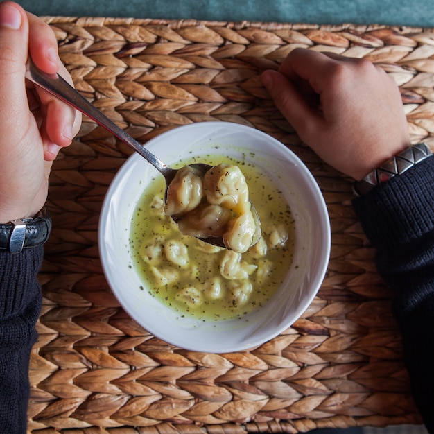 Free photo top view dushpara with spoon and human hand in plate