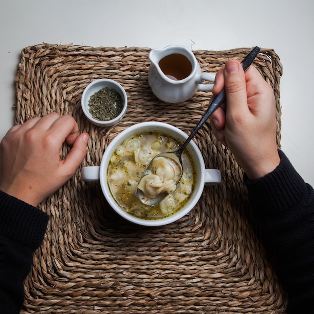 Free photo top view dushpara with vinegar and dried mint and human hand in serving napkins