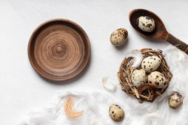 Top view of easter eggs in bird nest with feathers and empty plate