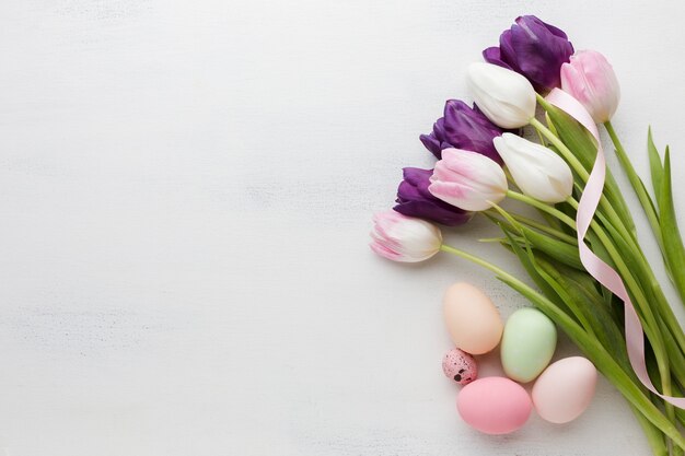 Top view of easter eggs with colorful tulips and copy space