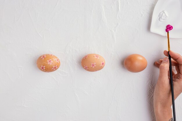 Top view of easter eggs with hand holding paintbrush