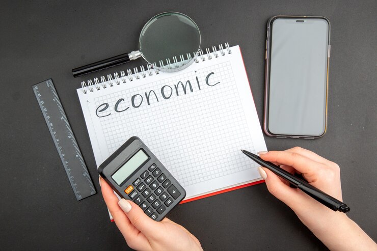 Free Photo top view economic written on spiral notepad lupa phone ruler pen and calculator in female hands on dark