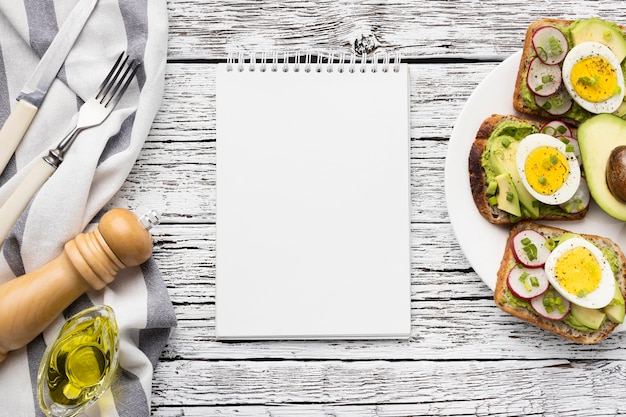 Top view of egg and avocado sandwiches on plate with notebook