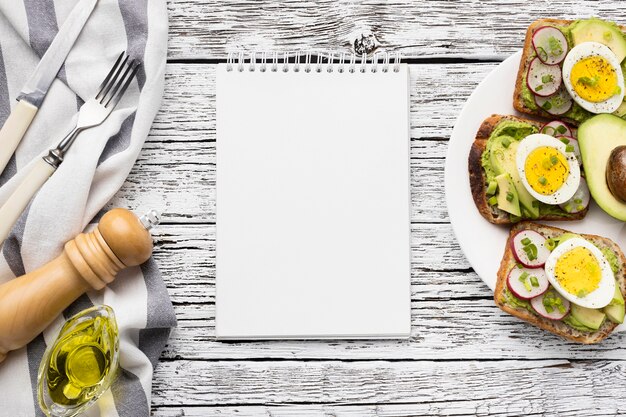 Top view of egg and avocado sandwiches on plate with notebook