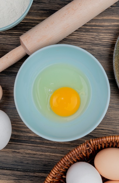 Free photo top view of egg white and yolk on a blue plate on a wooden background