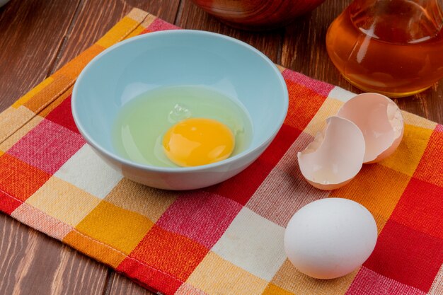 계란 노른자와 나무 배경에 식초와 체크 식탁보에 파란색 그릇에 흰색의 상위 뷰