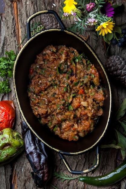 Top view eggplant caviar with tomato, parsley, basil in a pan vertical