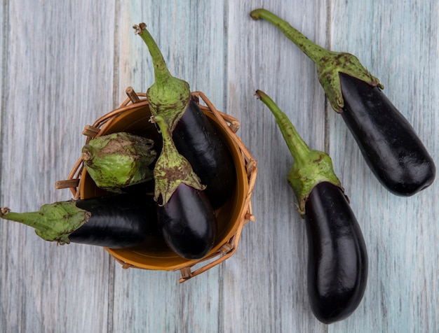 Free photo top view of eggplants in basket and on wooden background