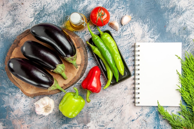 Top view eggplants on tree wood board with hot peppers on black plate