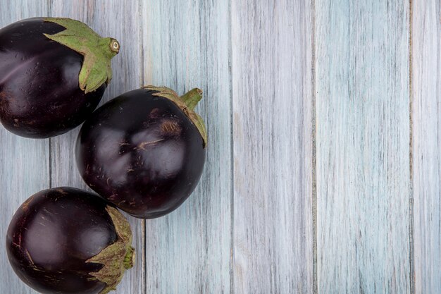 Top view of eggplants on wooden background with copy space