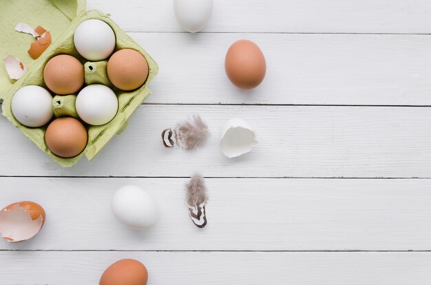 Top view of eggs in carton for easter with feathers and copy space