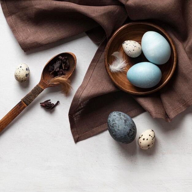 Top view of eggs for easter on plate with wooden spoon and feathers