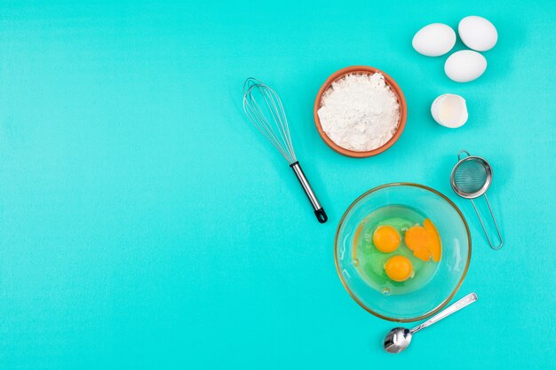 Top view of eggs with flour and copy space on blue background horizontal