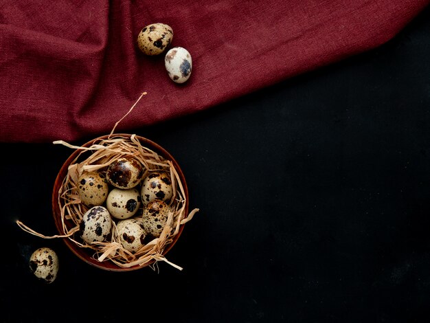 Free photo top view of eggs with nest in bowl on burgundy and black background with copy space