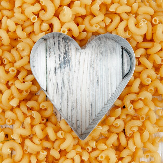 Top view elbow macaroni pasta with copy space on white wooden background