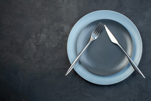 Top view elegant plates with knife and fork on dark background hunger silverware femininity colourful diner