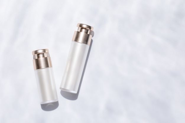 Top view of elegant skincare bottles on a white textured surface